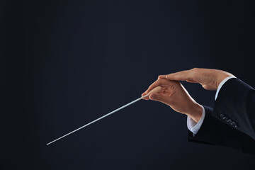 Professional conductor with baton on black background, closeup. Space for text