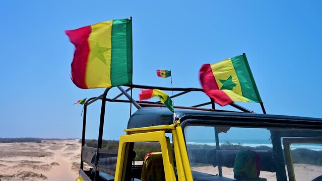 Senegal flags on a SUV blowing in the windo on a beach near Dakar, Senegal