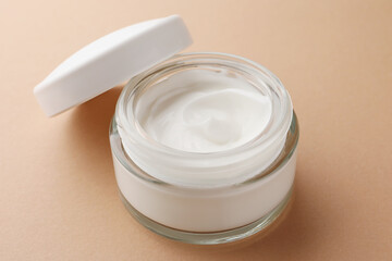 Jar of face cream on beige background, closeup