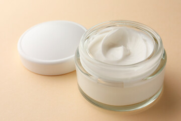 Jar of face cream on beige background, closeup