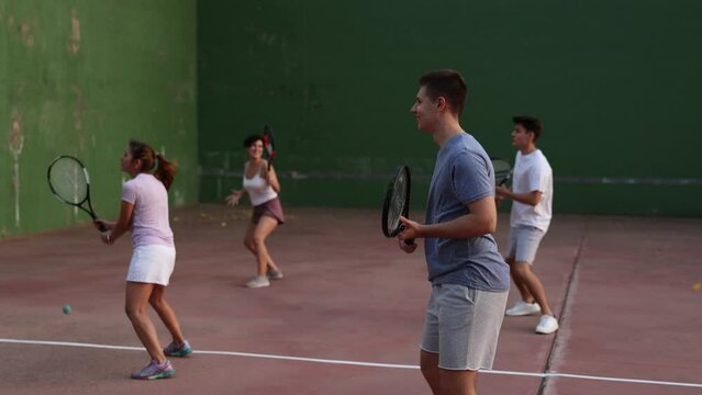 Group of sporty young people playing frontenis ball friendly match on outdoors court