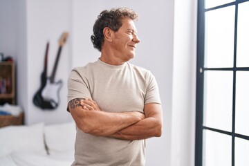Middle age man smiling confident standing with arms crossed gesture at bedroom