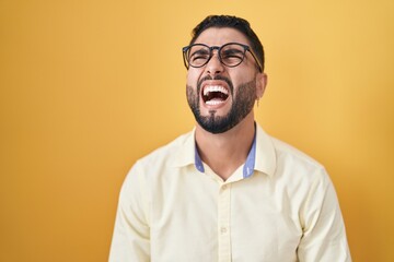 Obraz premium Hispanic young man wearing business clothes and glasses angry and mad screaming frustrated and furious, shouting with anger. rage and aggressive concept.