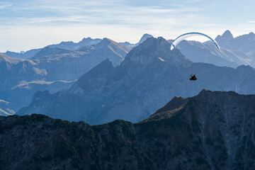 Paraglider flying above blue Mountains Silhouette, Allgaeu, Oberstdorf, Alps, Germany. Travel...