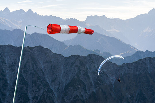 Windbag and Paraglider flying above Mountain Silhouette. Bad wind conditions. Allgaeu, Oberstdorf, Alps, Germany. Concept for creative business ideas.