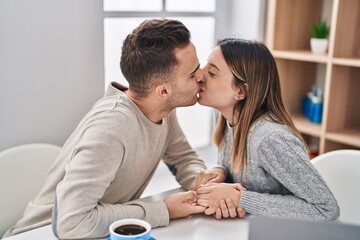 Man and woman couple using laptop and kissing at home