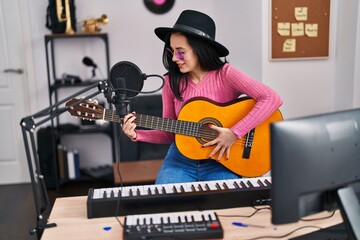 Young caucasian woman musician smiling confident playing classical guitar at music studio