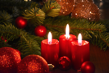 Obraz na płótnie Canvas Beautiful christmas decoration with burning red candles and fir tree branch stock images. Burning candles and red Christmas balls still life stock photo. Christmas candle lights background images