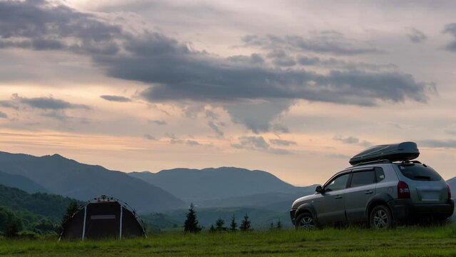 Summer evening landscape timelapse moving clouds Carpathian Mountains, Pryslip pass Ukraine. top of the mountain. A tourist tent and a SUV vehicle with a roof rack. concept of travel by car, Kolochava