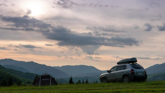 Summer evening landscape timelapse moving clouds Carpathian Mountains, Pryslip pass Ukraine. top of the mountain. A tourist tent and a SUV vehicle with a roof rack. concept of travel by car, Kolochava