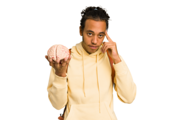 Young African American man holding a brain isolated pointing temple with finger, thinking, focused on a task.
