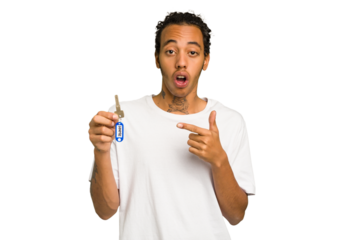 Young African American man holding home keys isolated pointing to the side