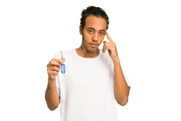 Young African American man holding home keys isolated pointing temple with finger, thinking, focused on a task.