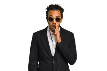 Young African American bodyguard man isolated is saying a secret hot braking news and looking aside