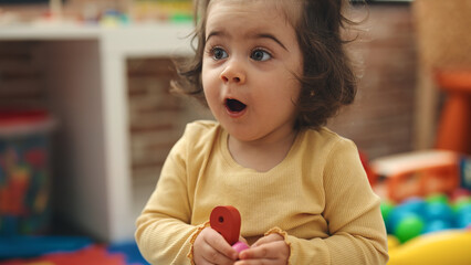 Adorable hispanic girl standing with surprise expression at kindergarten