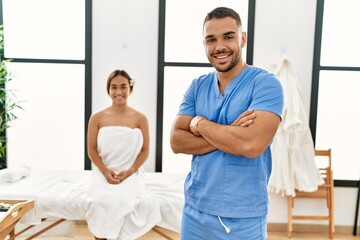 Latin man and woman wearing physiotherapy uniform standing with arms crossed gesture at beauty center