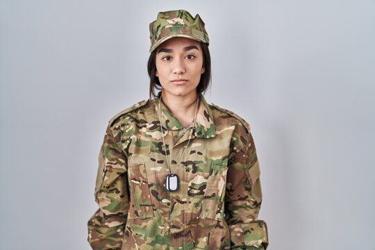Young south asian woman wearing camouflage army uniform relaxed with serious expression on face. simple and natural looking at the camera.