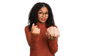 Young student african american woman holding a brain isolated pointing with finger at you as if...