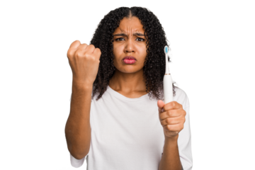 Young african american using a brushing teeth isolated showing fist to camera, aggressive facial expression.
