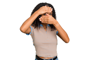 Young african american woman with curly hair cut out isolated blink at the camera through fingers, embarrassed covering face.