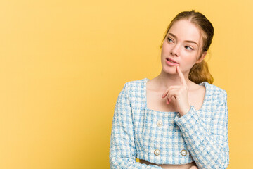 Young caucasian redhead woman isolated on yellow background looking sideways with doubtful and...