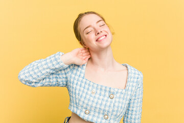 Young caucasian redhead woman isolated on yellow background feeling confident, with hands behind the head.