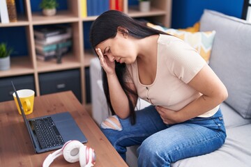 Young beautiful hispanic woman suffering for head and stomach ache at home
