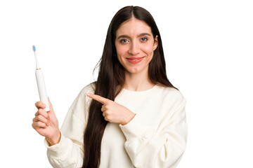 Young caucasian holding a brushing teeth isolated smiling and pointing aside, showing something at blank space.