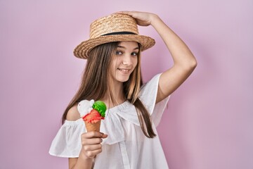 Teenager girl holding ice cream smiling confident touching hair with hand up gesture, posing attractive and fashionable