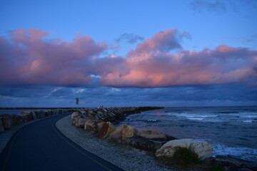 Clouds become pink-orange at sunset time over the sea at Yamba breakwater walkway, NSW, Australia