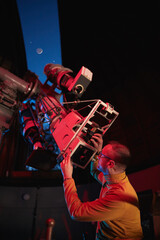 Astronomer with a big astronomical telescope in observatory doing science research of space and...