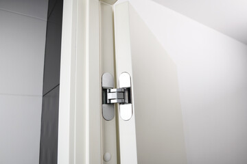 New modern metal door hinges hidden on white wooden doors.