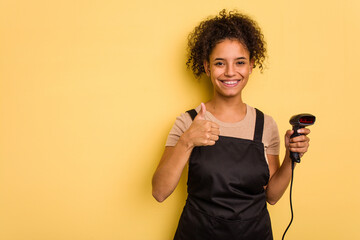 Young brazilian work woman holding a hand sticker price label machine isolatedYoung brazilian woman holdismiling and raising thumb up