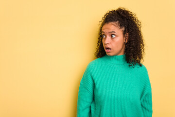 Young Brazilian curly hair cute woman isolated on yellow background being shocked because of something she has seen.