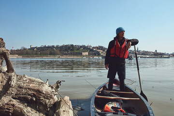 Man paddling in a canoe on a Danube river in urban area, small recreational escape, hobbies and...