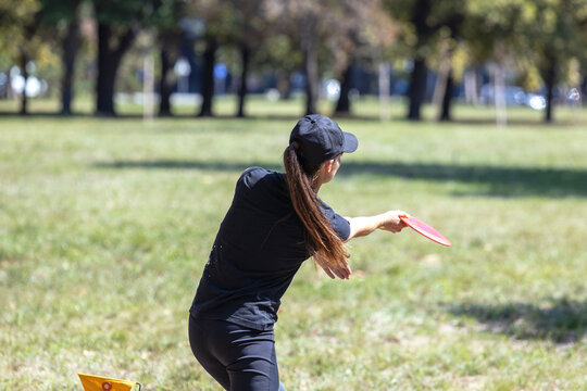 Disc golf player throwing a flying disc in the park