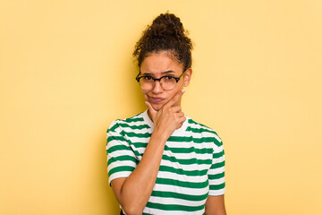 Young Brazilian curly hair cute woman isolated on yellow background contemplating, planning a strategy, thinking about the way of a business.