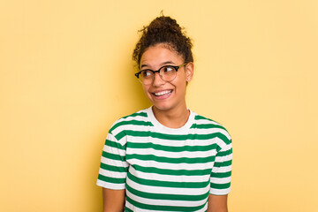 Young Brazilian curly hair cute woman isolated on yellow background laughs and closes eyes, feels relaxed and happy.