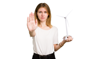 Young caucasian woman holding a small wind energy mill isolated standing with outstretched hand showing stop sign, preventing you.