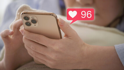 スマートフォンを操作をするパジャマ姿の若い女性