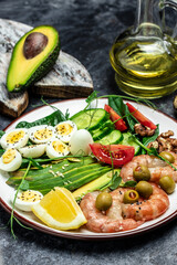 shrimps, prawns, soft fried egg, fresh salad, tomatoes, cucumbers and avocado on a light background. Ketogenic diet breakfast. Keto, paleo lunch. Top view