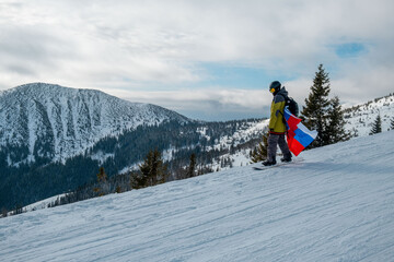 man snowboarder with slovakia flag at ski resort slope