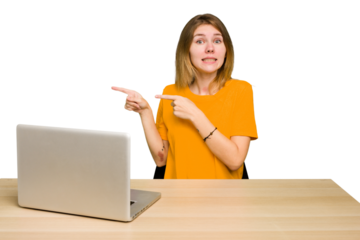 Young caucasian woman in a workplace working with a laptop isolated shocked pointing with index fingers to a copy space.