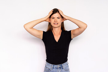 Portrait of depressed young woman looking at camera over white background. Caucasian lady wearing black T-shirt and jeans regretting mistatake or forgetting something. Anxiety and stress concept