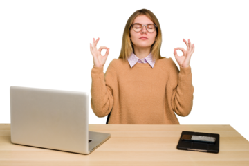 Young caucasian woman in a workplace working with a laptop isolated relaxes after hard working day, she is performing yoga.