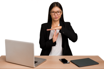 Young business asian woman sitting on a table isolated showing a timeout gesture.