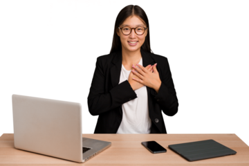 Young business asian woman sitting on a table isolated has friendly expression, pressing palm to chest. Love concept.