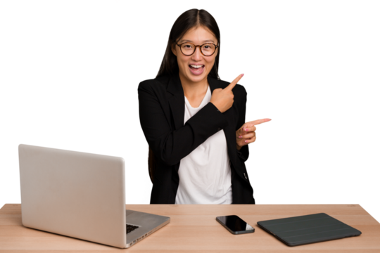 Young business asian woman sitting on a table isolated pointing with forefingers to a copy space, expressing excitement and desire.