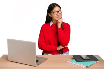 Young student asian woman in a workplace with a laptop isolated relaxed thinking about something looking at a copy space.