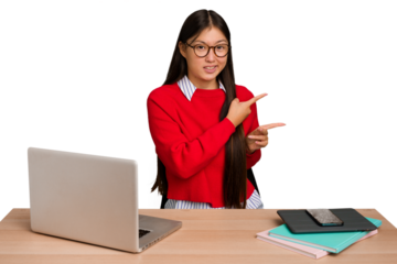 Young student asian woman in a workplace with a laptop isolated shocked pointing with index fingers to a copy space.